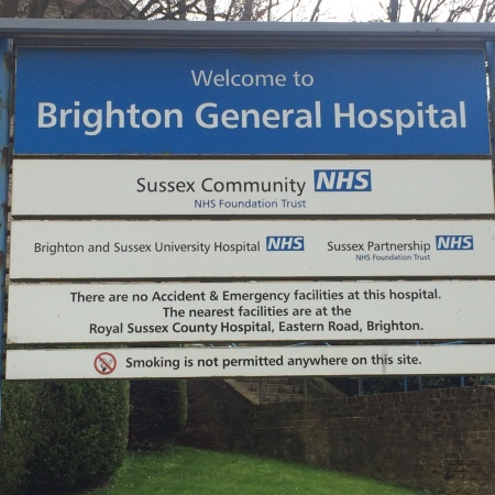A large sign outside Brighton General Hospital, stating that it is the location of Sussex Partnership NHS Foundation Trust.